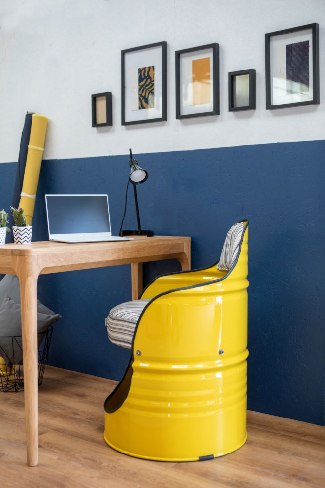 Ejemplo de despacho urbano con paredes azules, suelo laminado y escritorio independiente
