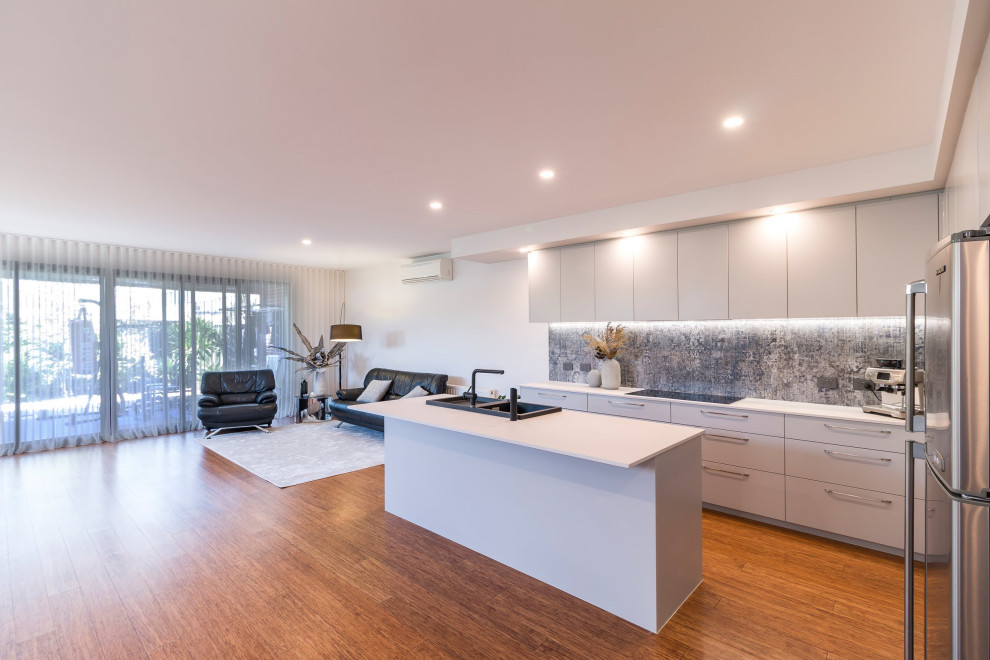 Photo of a mid-sized contemporary eat-in kitchen in Melbourne with a drop-in sink, grey cabinets, quartz benchtops, black appliances, bamboo floors, with island, brown floor and white benchtop.