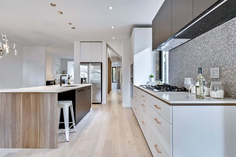 Photo of a mid-sized contemporary galley eat-in kitchen in Toronto with a double-bowl sink, flat-panel cabinets, black cabinets, quartz benchtops, multi-coloured splashback, mosaic tile splashback, panelled appliances, light hardwood floors and with island.