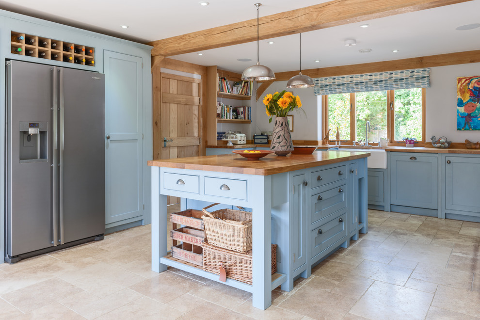 This is an example of a country u-shaped kitchen in Surrey with a farmhouse sink, shaker cabinets, blue cabinets, wood benchtops, stainless steel appliances, with island and beige floor.