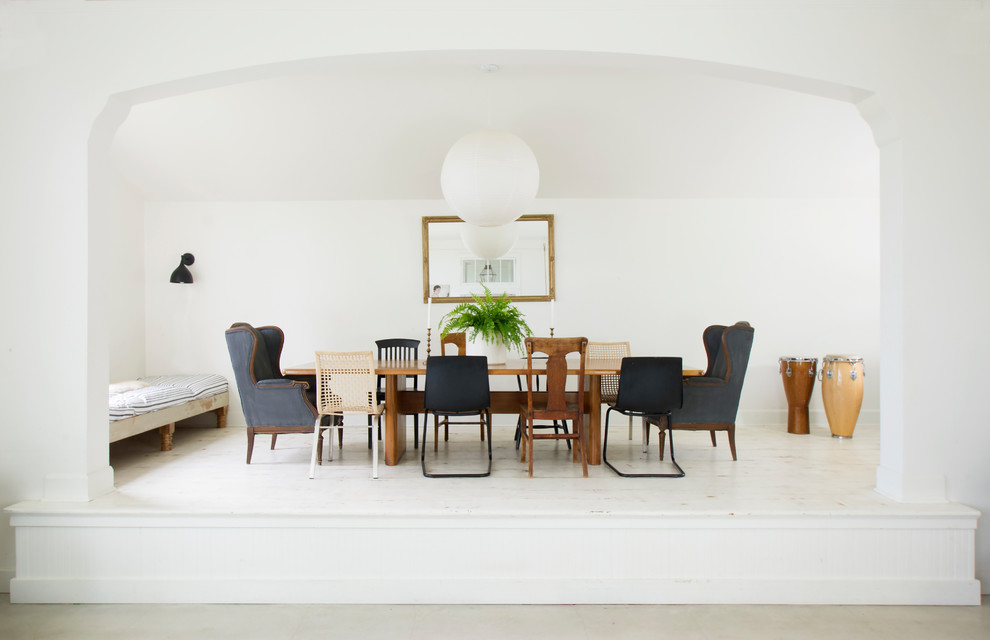 This is an example of an eclectic separate dining room in San Francisco with white walls, painted wood floors and white floor.