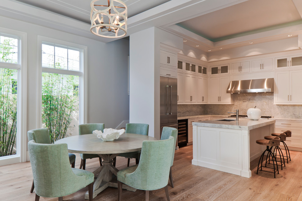 Example of a large transitional l-shaped light wood floor and tray ceiling open concept kitchen design in Miami with an undermount sink, shaker cabinets, white cabinets, quartz countertops, gray backsplash, quartz backsplash, stainless steel appliances, an island and gray countertops
