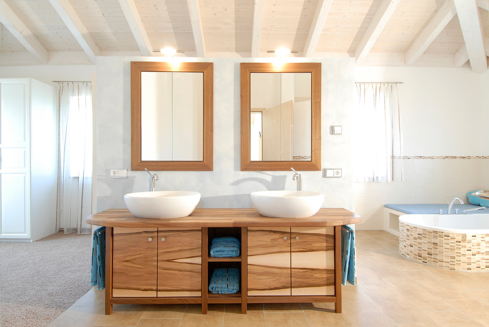 Inspiration for a large contemporary master bathroom in Munich with a vessel sink, flat-panel cabinets, medium wood cabinets, mosaic tile, white walls, wood benchtops, beige tile and a drop-in tub.
