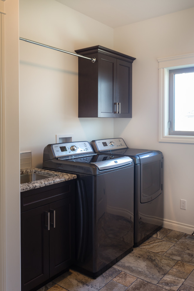 Photo of a small transitional single-wall dedicated laundry room in Calgary with an undermount sink, shaker cabinets, dark wood cabinets, granite benchtops, white walls, ceramic floors and a side-by-side washer and dryer.