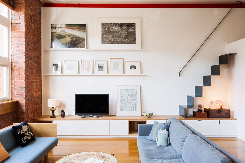 Idee per un piccolo soggiorno contemporaneo aperto con pareti bianche, pavimento in legno massello medio, TV autoportante, pavimento marrone e pareti in mattoni
