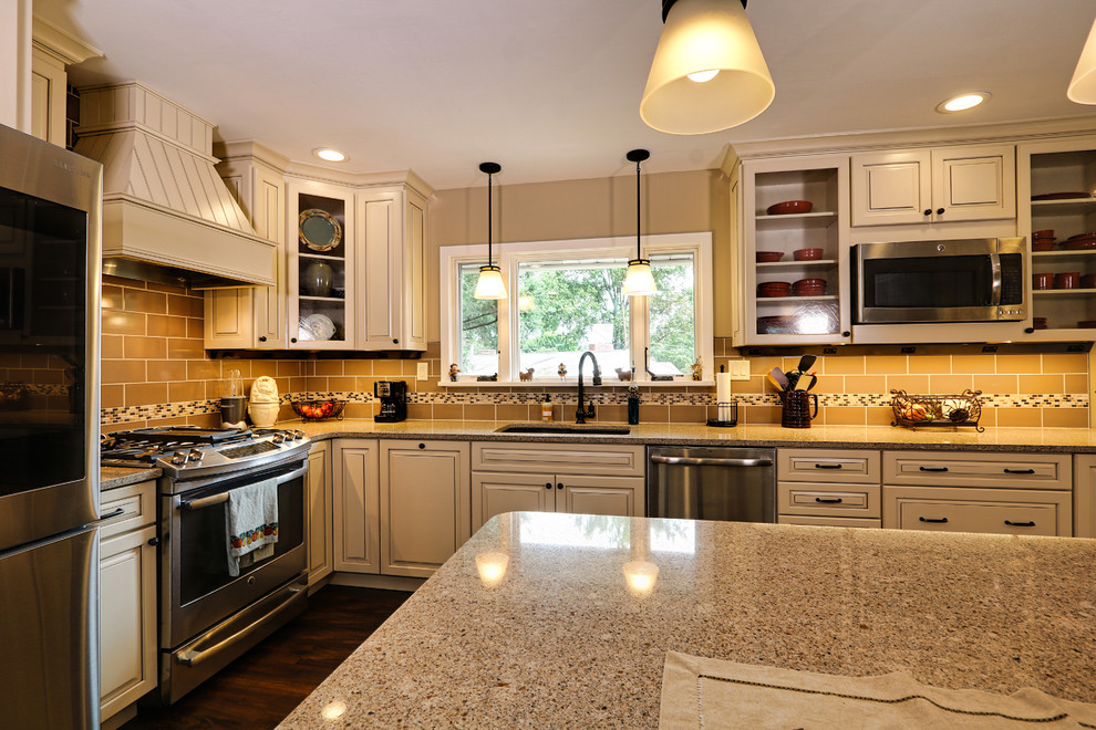 Example of a mid-sized transitional u-shaped vinyl floor and brown floor eat-in kitchen design with an undermount sink, raised-panel cabinets, beige cabinets, quartz countertops, brown backsplash, porcelain backsplash, stainless steel appliances and an island