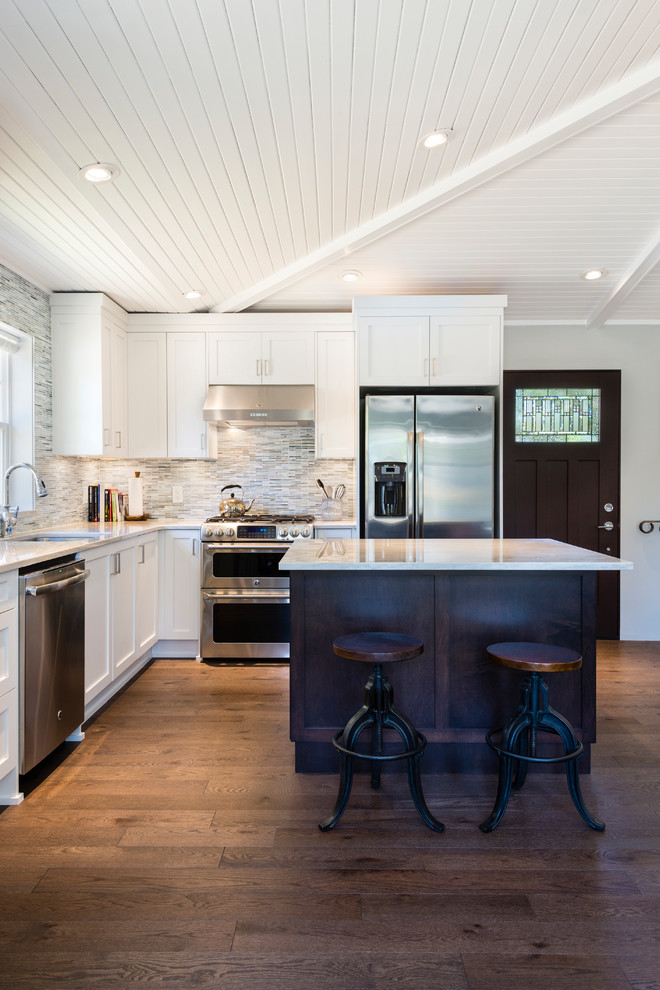 Inspiration for a small transitional l-shaped medium tone wood floor and brown floor open concept kitchen remodel in Vancouver with an undermount sink, recessed-panel cabinets, white cabinets, quartzite countertops, gray backsplash, matchstick tile backsplash, stainless steel appliances and an island