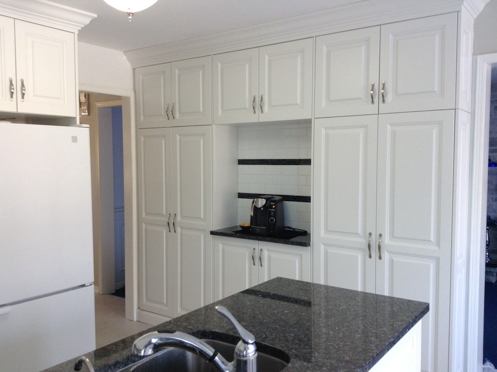 Kitchen pantry - kitchen pantry idea in Other with raised-panel cabinets, white cabinets, granite countertops and white backsplash