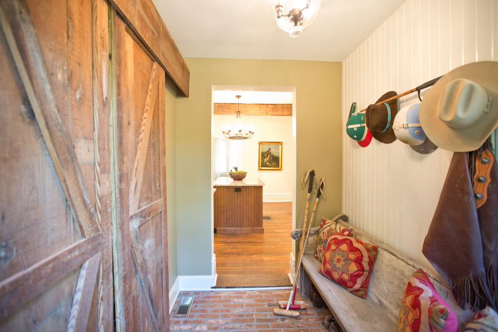 Inspiration for a country entryway in Other with green walls, brick floors and red floor.
