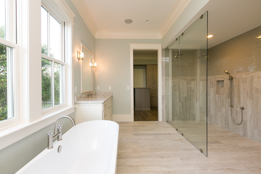 Inspiration for a large beach style master bathroom in Charleston with shaker cabinets, white cabinets, a freestanding tub, a curbless shower, a two-piece toilet, beige tile, porcelain tile, blue walls, porcelain floors, an undermount sink and engineered quartz benchtops.