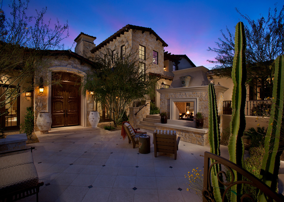 This is an example of a large mediterranean patio in Phoenix with a fire feature, no cover and tile.