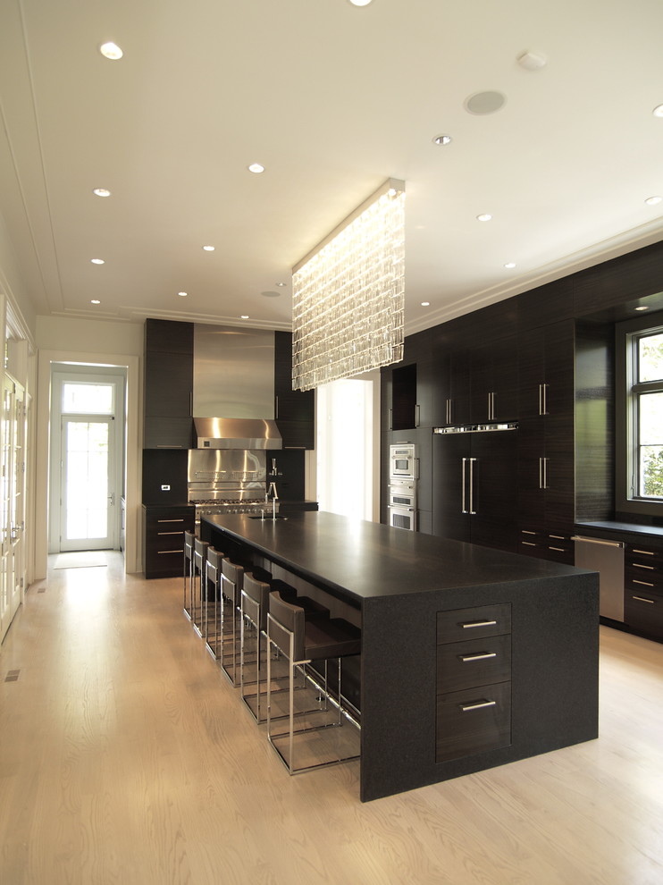 Contemporary kitchen in Atlanta with panelled appliances, flat-panel cabinets, black cabinets and granite benchtops.