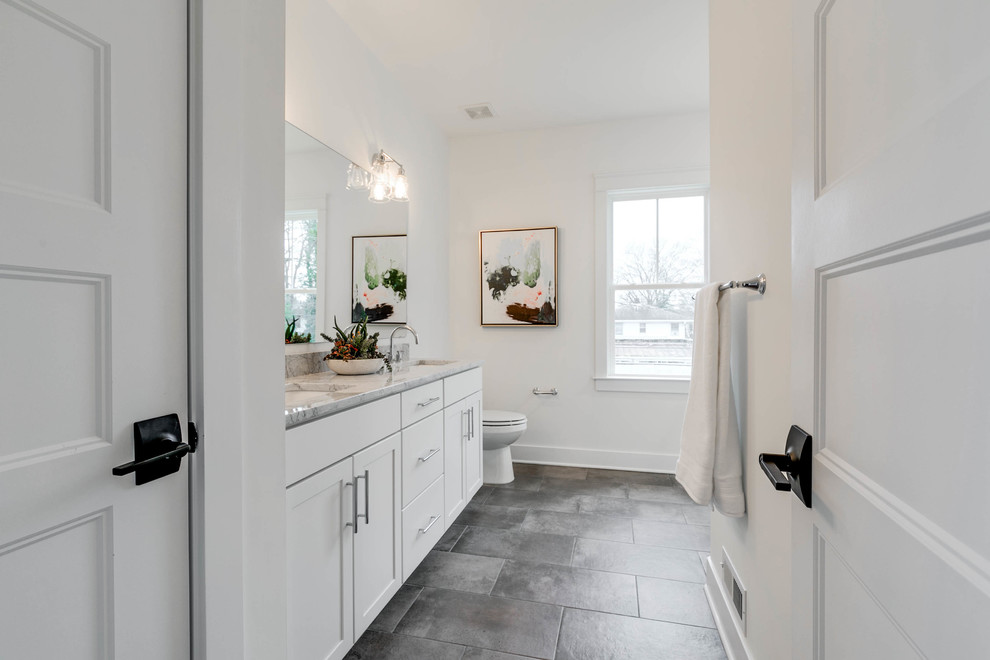 Photo of a mid-sized scandinavian master bathroom in Richmond with shaker cabinets, white cabinets, a corner shower, a two-piece toilet, white tile, ceramic tile, white walls, ceramic floors, an undermount sink, marble benchtops, grey floor, a hinged shower door and grey benchtops.