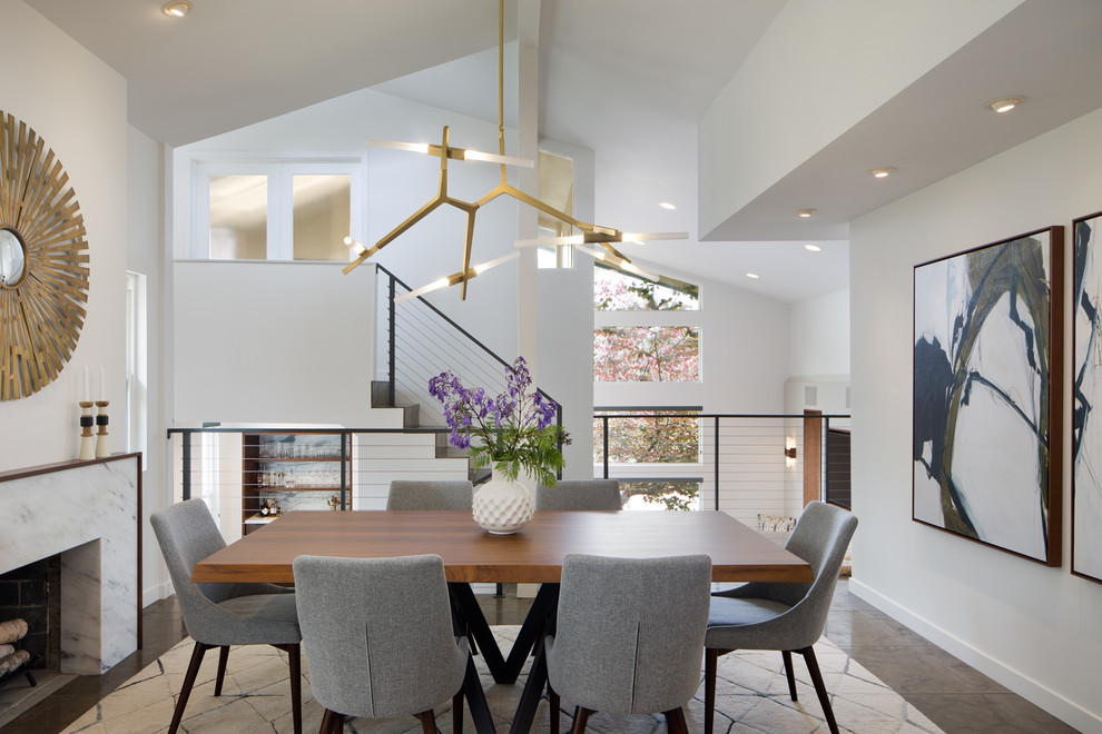 This is an example of a contemporary dining room in San Diego with white walls, a standard fireplace and a stone fireplace surround.