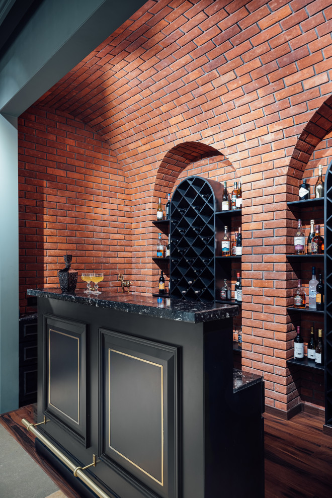 Design ideas for a traditional home bar in Pune with open cabinets, dark hardwood floors and black benchtop.