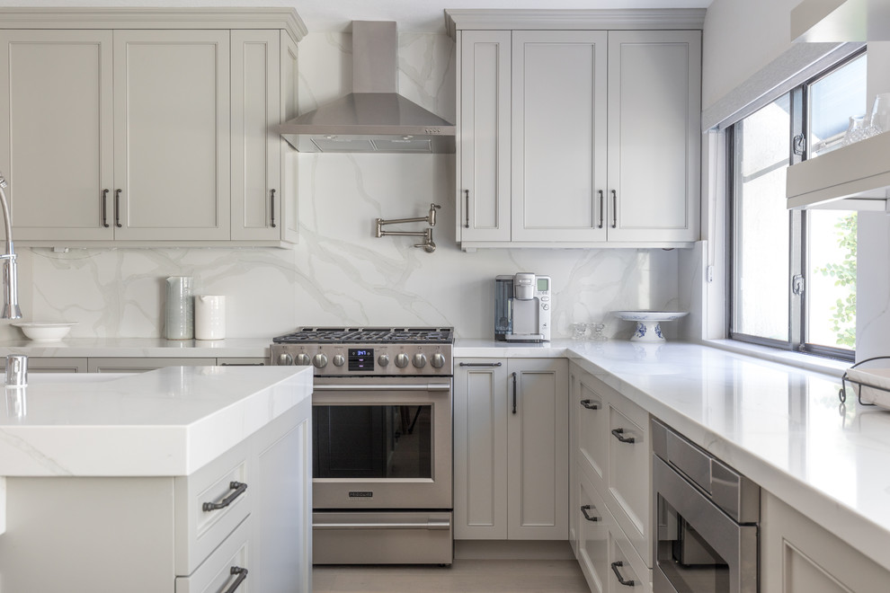Inspiration for a mid-sized transitional u-shaped light wood floor and brown floor open concept kitchen remodel in Orange County with gray cabinets, quartz countertops, white backsplash, marble backsplash, stainless steel appliances, an island, white countertops, a farmhouse sink and recessed-panel cabinets