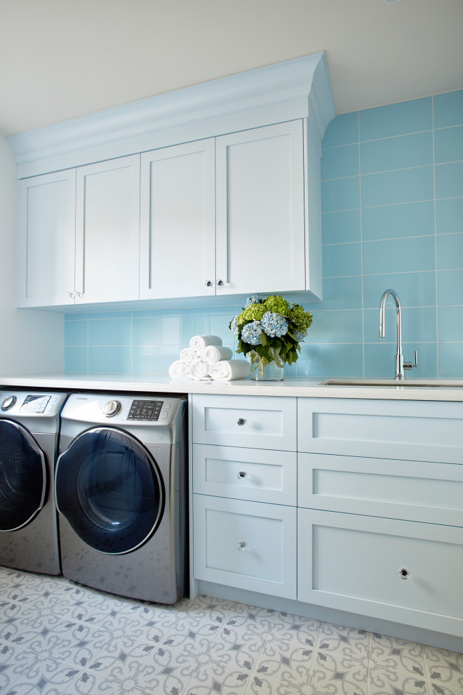 Mid-sized country single-wall dedicated laundry room in Toronto with an undermount sink, shaker cabinets, blue cabinets, quartz benchtops, blue splashback, glass tile splashback, blue walls, ceramic floors, a side-by-side washer and dryer and white benchtop.