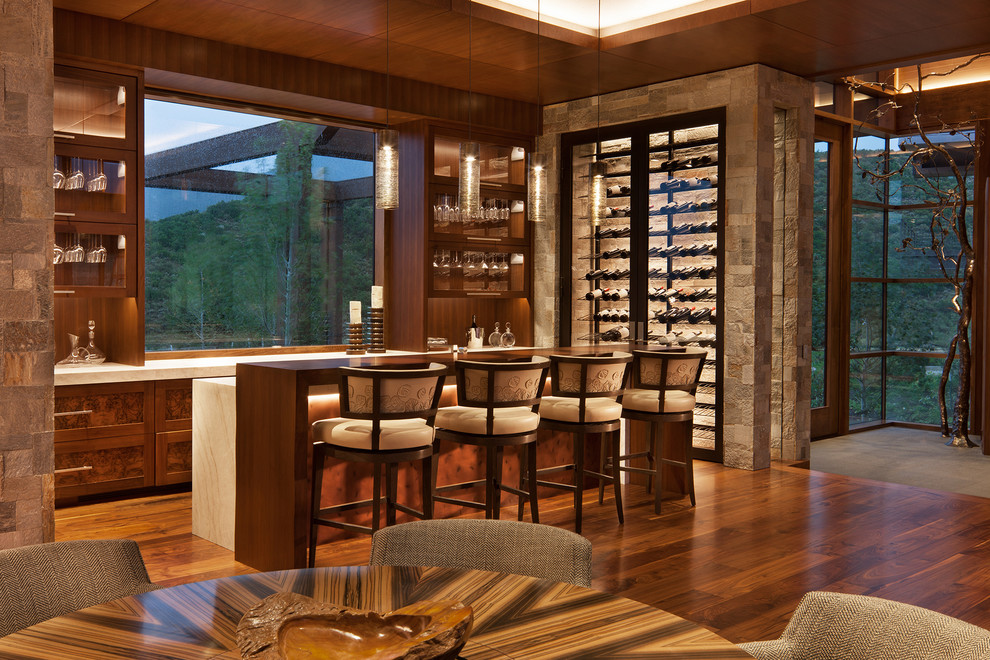 Design ideas for a country l-shaped seated home bar in Denver with recessed-panel cabinets, brown cabinets, medium hardwood floors, brown floor and beige benchtop.