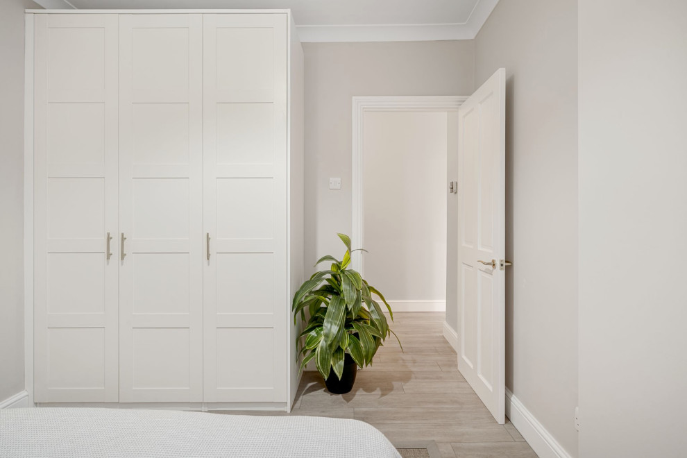 На фото: хозяйская спальня среднего размера в современном стиле с бежевыми стенами, полом из ламината и коричневым полом с