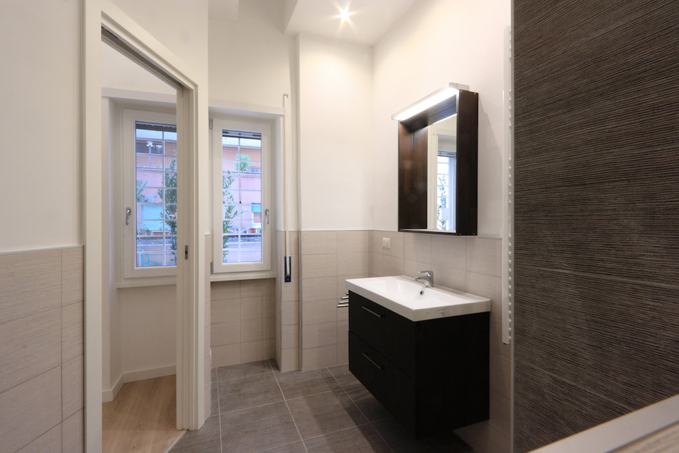 This is an example of a small contemporary bathroom in Rome with an alcove shower, a two-piece toilet, black and white tile, porcelain tile, white walls, porcelain floors, a trough sink, black floor and a hinged shower door.