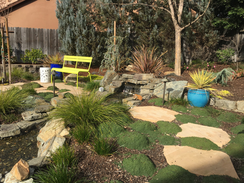 Idee per un giardino xeriscape mediterraneo esposto in pieno sole dietro casa in estate con sassi e rocce e pavimentazioni in pietra naturale