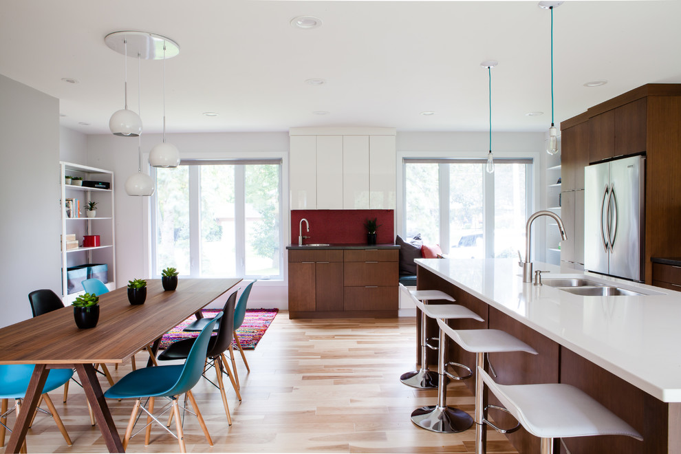 This is an example of a large scandinavian l-shaped eat-in kitchen in Toronto with an undermount sink, flat-panel cabinets, white cabinets, quartz benchtops, red splashback, ceramic splashback, stainless steel appliances, medium hardwood floors and with island.