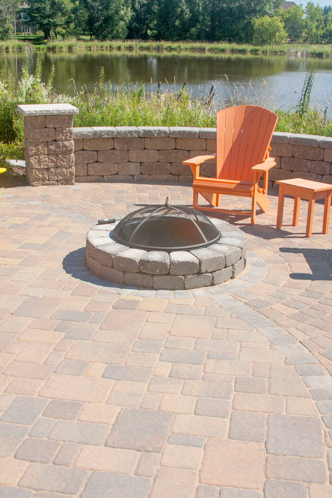 Design ideas for a mid-sized traditional backyard patio in Minneapolis with concrete pavers, a roof extension and a fire feature.