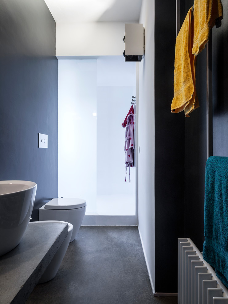 This is an example of an industrial bathroom in New York with a bidet, black walls, a vessel sink, concrete benchtops, grey floor and grey benchtops.