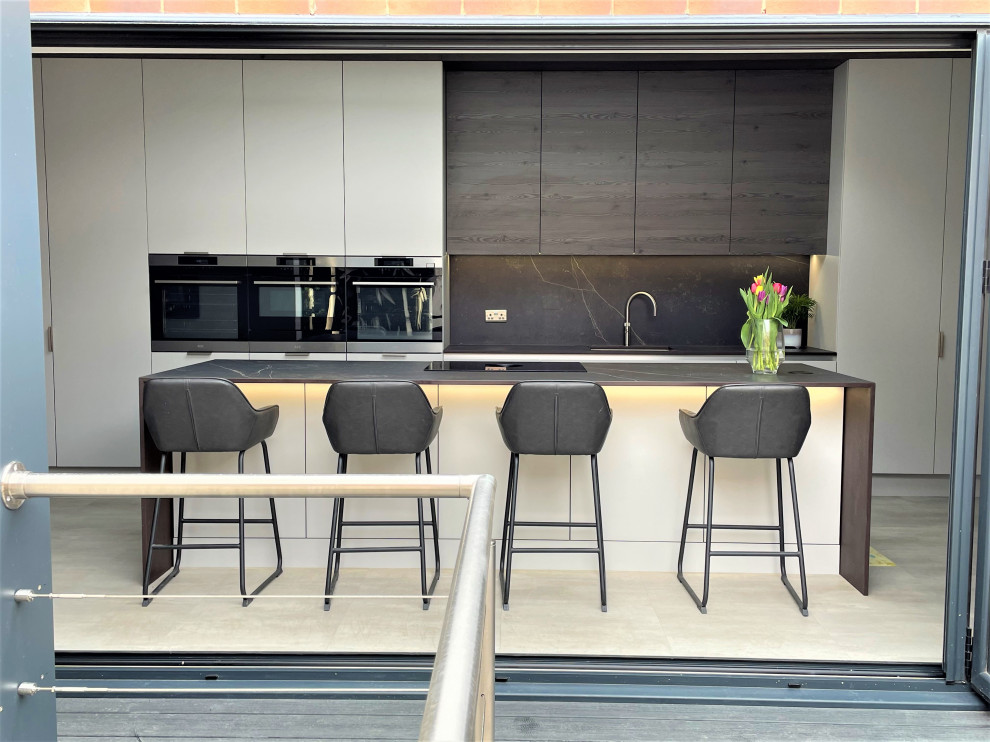 Large contemporary grey and brown single-wall open plan kitchen in Other with a single-bowl sink, flat-panel cabinets, medium wood cabinets, engineered stone countertops, grey splashback, black appliances, vinyl flooring, an island, grey floors, grey worktops and a chimney breast.