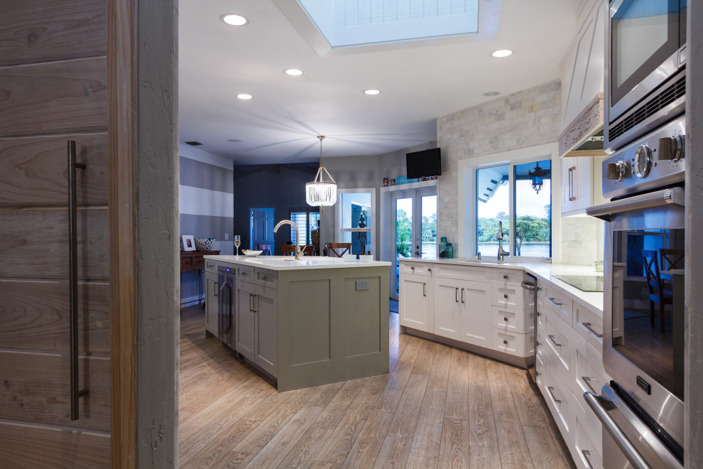 Kitchen - large transitional u-shaped light wood floor and beige floor kitchen idea in Miami with a single-bowl sink, recessed-panel cabinets, white cabinets, quartz countertops, white backsplash, subway tile backsplash, stainless steel appliances, an island and white countertops