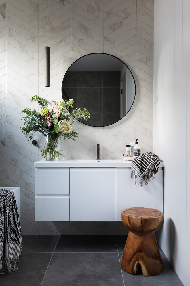 This is an example of a modern bathroom in Canberra - Queanbeyan with white cabinets, a wall-mount toilet, gray tile, porcelain tile, porcelain floors, an integrated sink and grey floor.