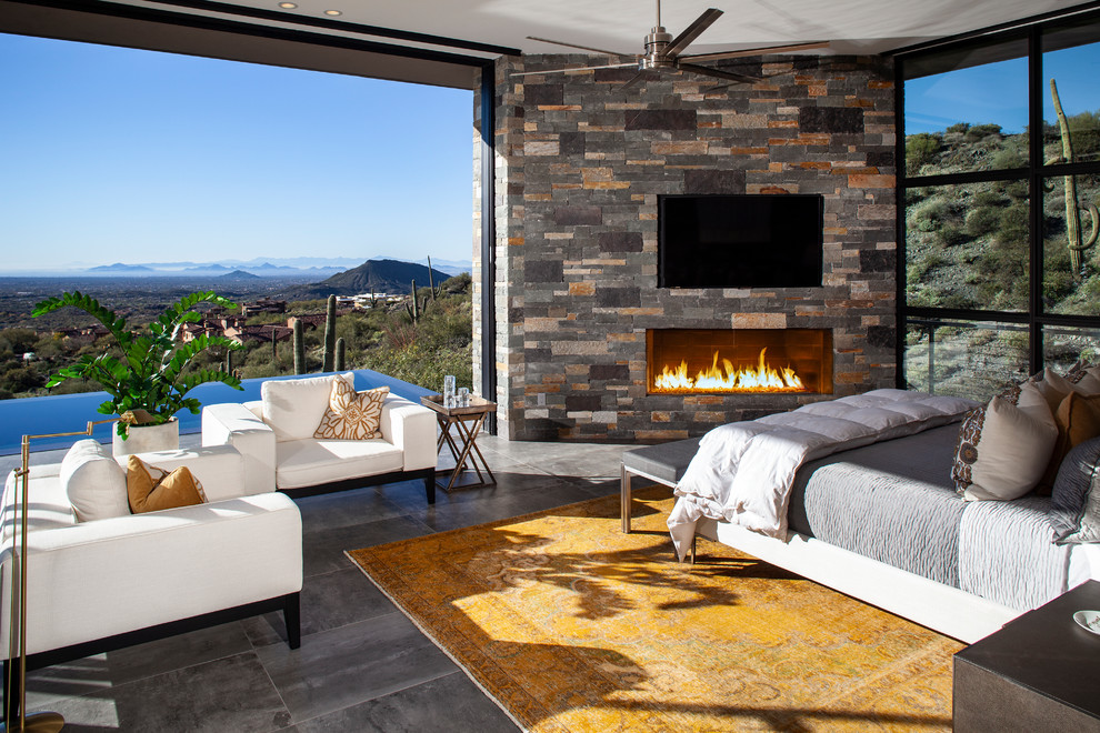 Inspiration for an expansive contemporary master bedroom in Phoenix with a stone fireplace surround, grey floor, porcelain floors and a corner fireplace.