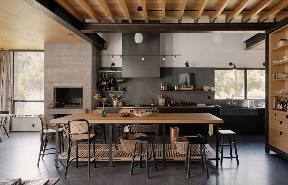 Inspiration for a country eat-in kitchen in Other with a farmhouse sink, wood benchtops, stainless steel appliances, concrete floors, open cabinets, light wood cabinets, grey splashback, with island, black floor and brown benchtop.