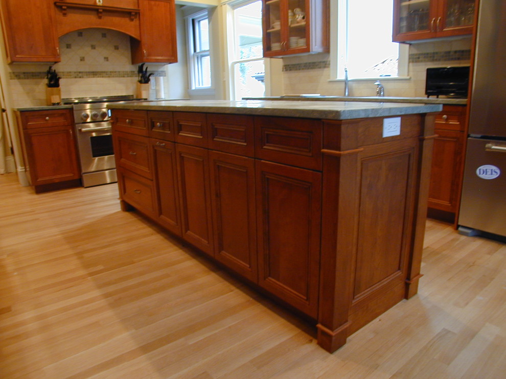 Example of a mid-sized transitional galley light wood floor eat-in kitchen design in Boston with an undermount sink, recessed-panel cabinets, dark wood cabinets, granite countertops, beige backsplash, stone tile backsplash, stainless steel appliances and an island