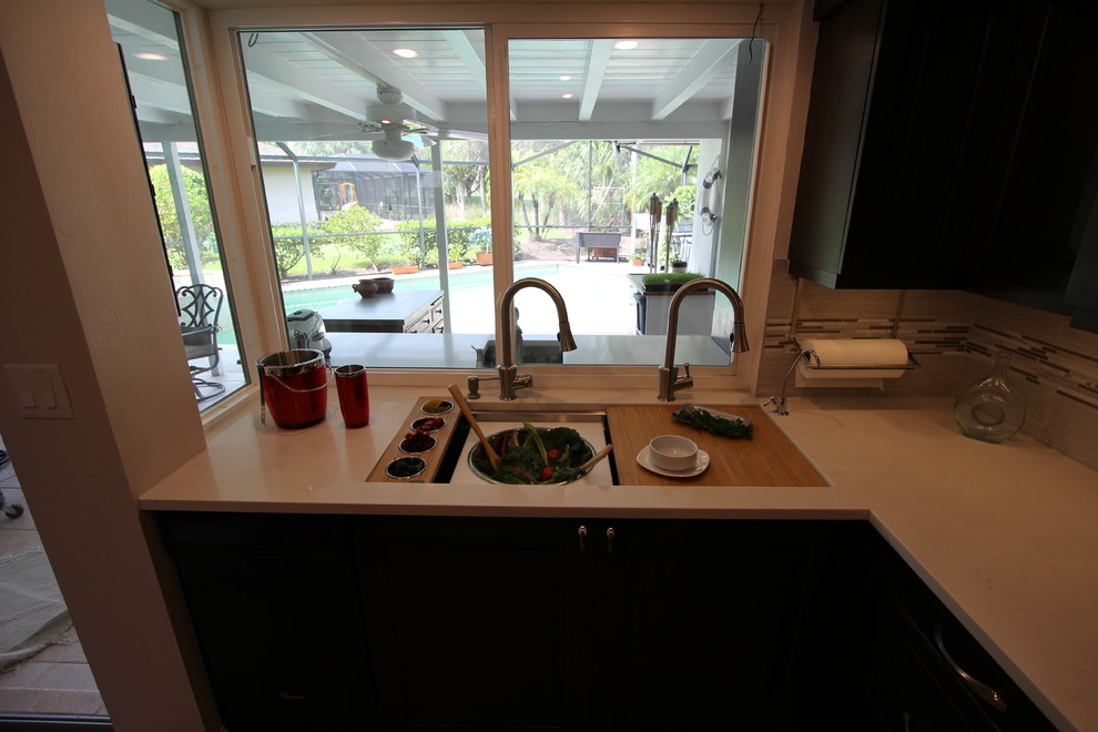 Example of a transitional l-shaped eat-in kitchen design in Miami with an undermount sink, flat-panel cabinets, gray cabinets, quartzite countertops, white backsplash, subway tile backsplash, black appliances and an island