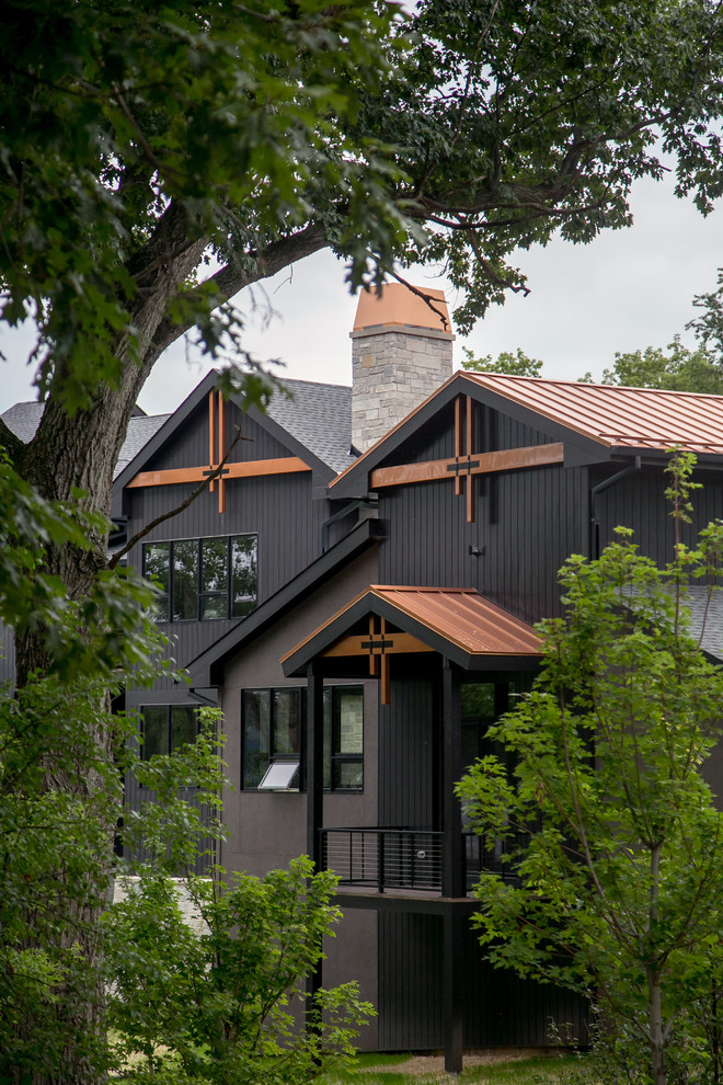 This is an example of a large contemporary three-storey black house exterior in Milwaukee with mixed siding, a gable roof and a mixed roof.