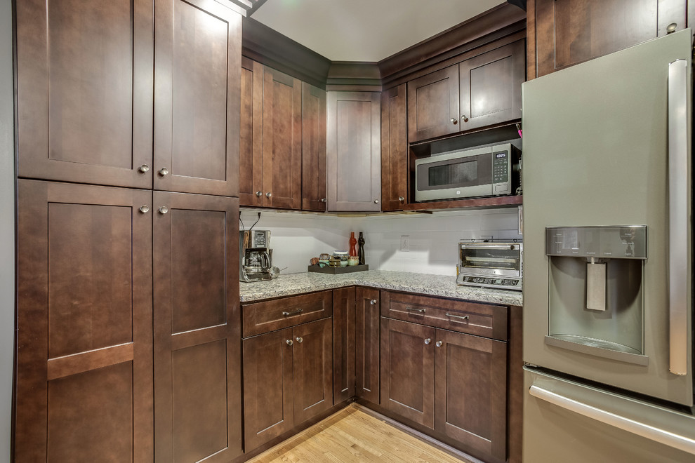Eat-in kitchen - mid-sized transitional l-shaped light wood floor and yellow floor eat-in kitchen idea in Birmingham with a double-bowl sink, shaker cabinets, dark wood cabinets, granite countertops, white backsplash, subway tile backsplash, stainless steel appliances, an island and gray countertops