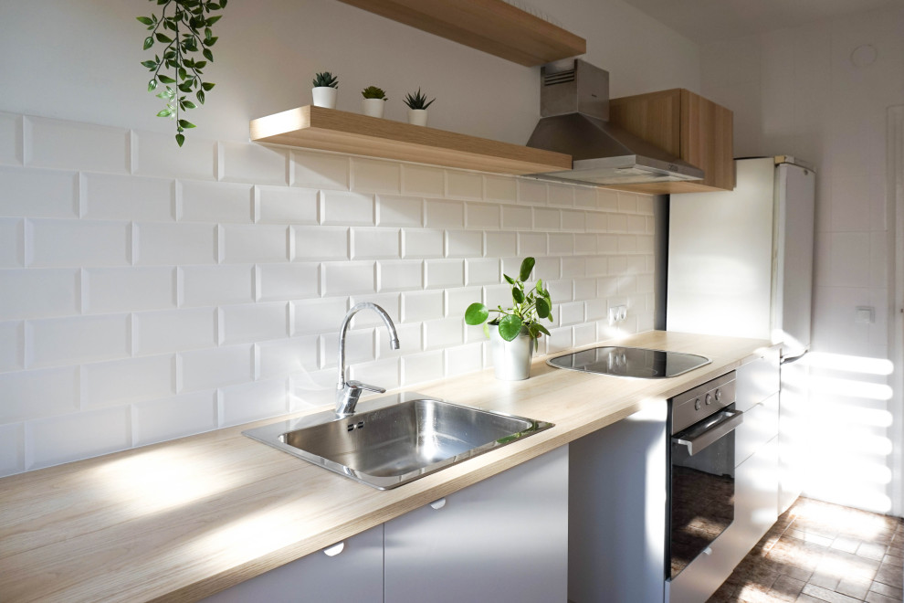 Mid-sized scandinavian single-wall separate kitchen in Barcelona with a single-bowl sink, flat-panel cabinets, white cabinets, laminate benchtops, white splashback, ceramic splashback, black appliances, ceramic floors, no island, brown floor and beige benchtop.