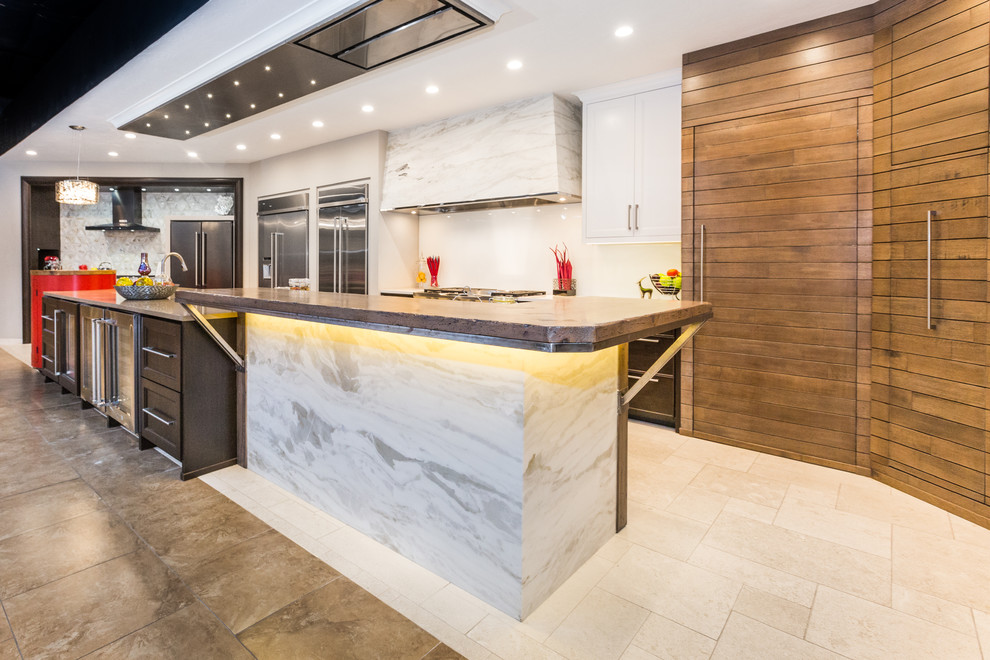 This is an example of a large contemporary u-shaped eat-in kitchen in Albuquerque with an integrated sink, quartz benchtops, glass sheet splashback, stainless steel appliances, porcelain floors, with island, shaker cabinets, dark wood cabinets and white splashback.