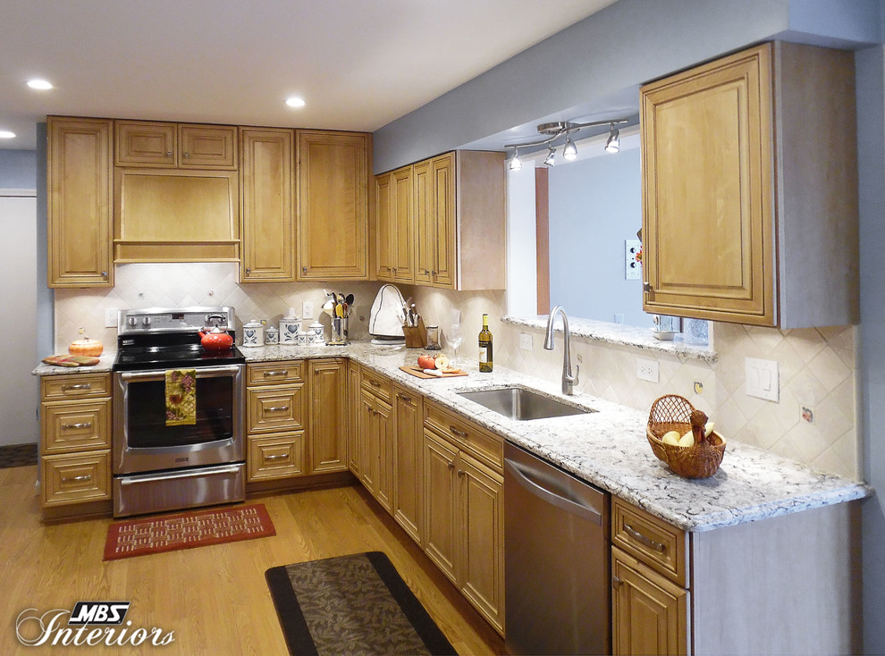 Example of a mid-sized transitional u-shaped light wood floor enclosed kitchen design in Detroit with an undermount sink, light wood cabinets, quartz countertops, white backsplash, stone tile backsplash, stainless steel appliances and no island