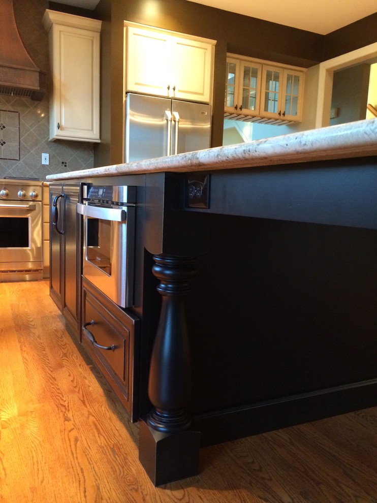 Kitchen - transitional l-shaped medium tone wood floor kitchen idea in St Louis with a farmhouse sink, raised-panel cabinets, granite countertops and an island
