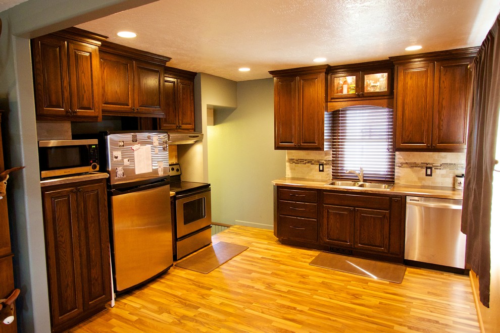 Inspiration for a small l-shaped kitchen remodel with a drop-in sink, dark wood cabinets, laminate countertops, beige backsplash, ceramic backsplash and stainless steel appliances