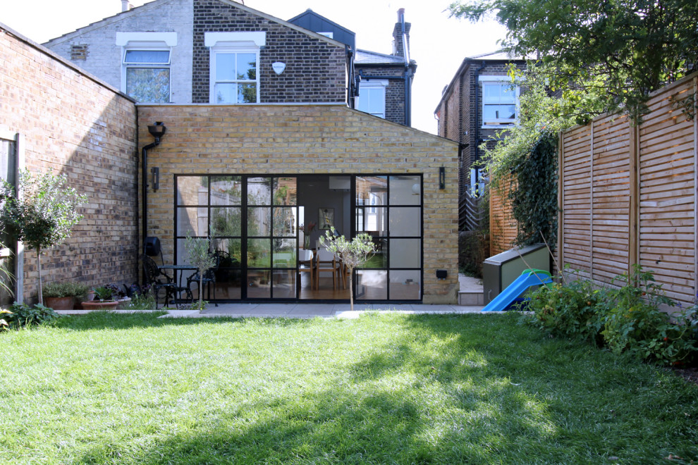 Geometrischer, Großer, Halbschattiger Moderner Garten im Frühling, hinter dem Haus mit Holzzaun in London