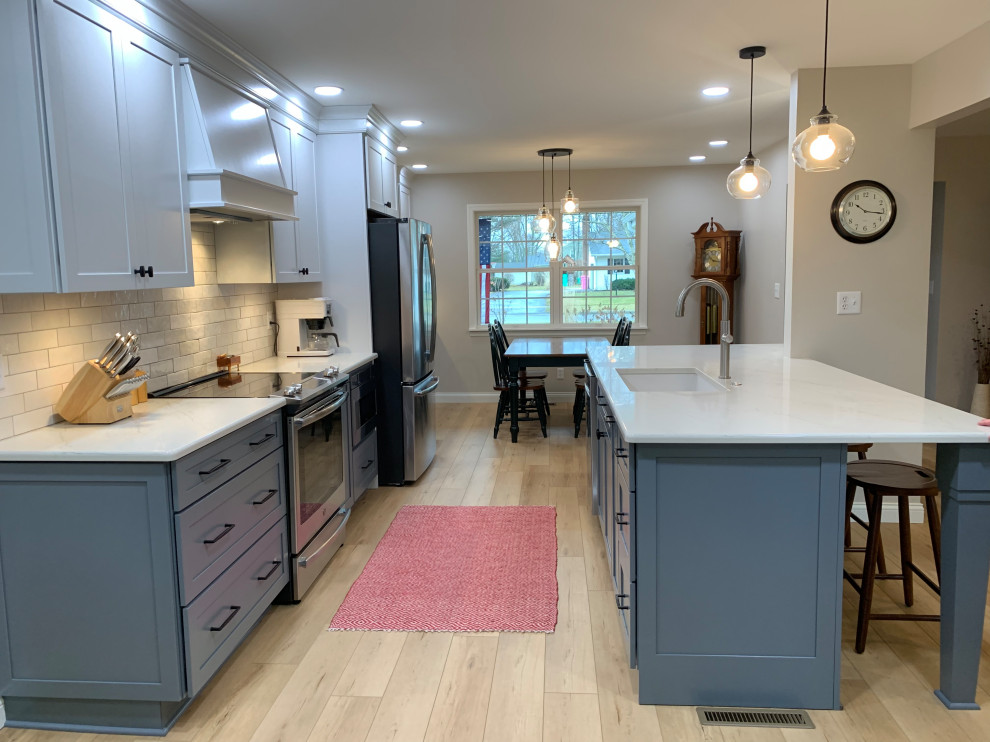 Design ideas for a mid-sized traditional galley open plan kitchen in Other with an undermount sink, shaker cabinets, blue cabinets, quartz benchtops, white splashback, stainless steel appliances, with island and white benchtop.