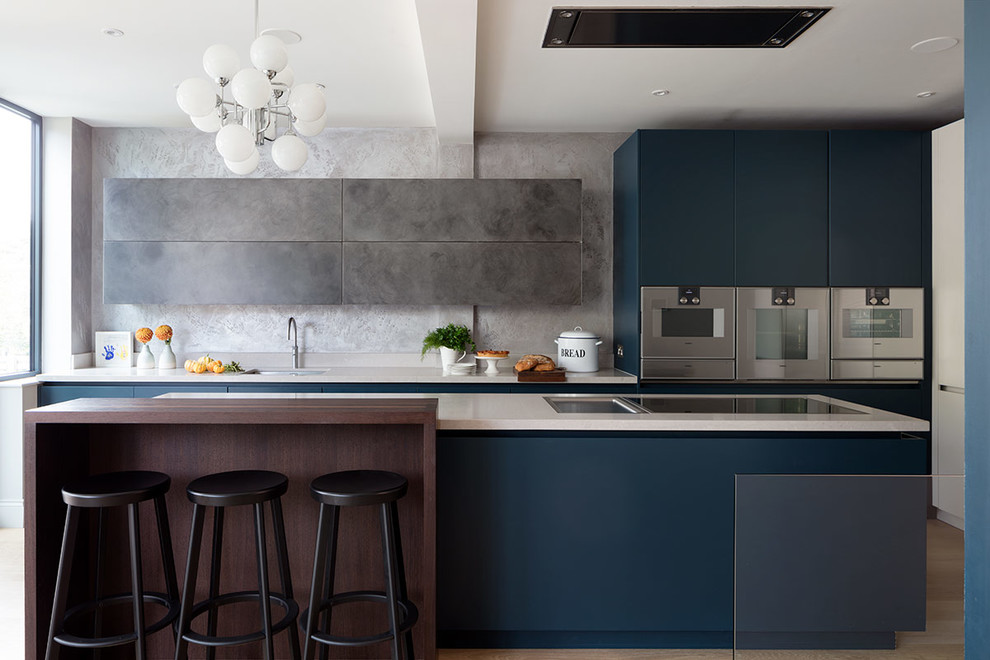Design ideas for a large contemporary galley kitchen in London with an undermount sink, quartz benchtops, grey splashback, light hardwood floors, with island, beige floor, white benchtop, flat-panel cabinets, blue cabinets and stainless steel appliances.
