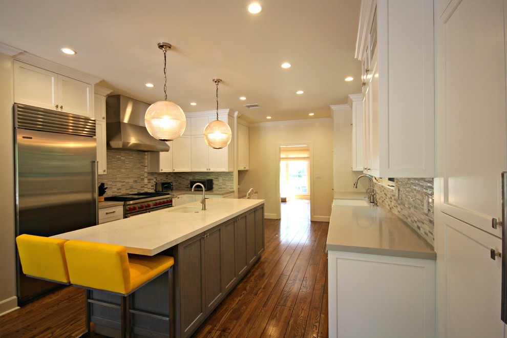 This is an example of a large transitional u-shaped eat-in kitchen in Los Angeles with shaker cabinets, white cabinets, multi-coloured splashback, matchstick tile splashback, stainless steel appliances, medium hardwood floors, with island, a farmhouse sink, quartz benchtops and beige floor.