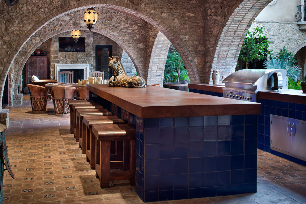 Inspiration for a mediterranean patio in Houston with an outdoor kitchen, tile and a roof extension.