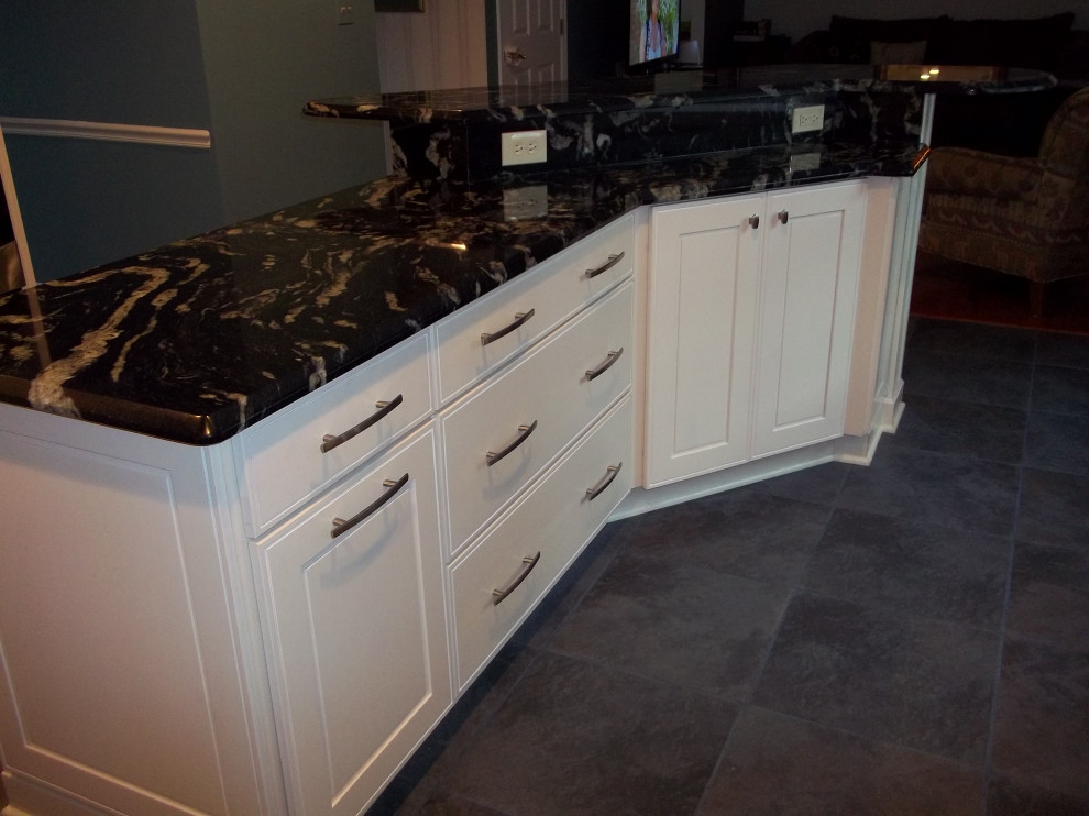 This is an example of a mid-sized traditional l-shaped eat-in kitchen in Other with an undermount sink, recessed-panel cabinets, white cabinets, granite benchtops, pink splashback, stainless steel appliances, slate floors, with island, multi-coloured floor and black benchtop.