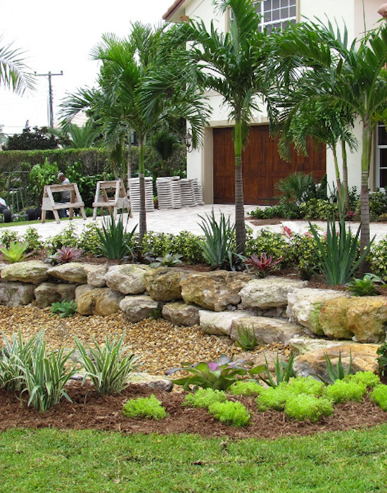Inspiration for a mid-sized tropical front yard partial sun driveway for spring in Miami with concrete pavers.