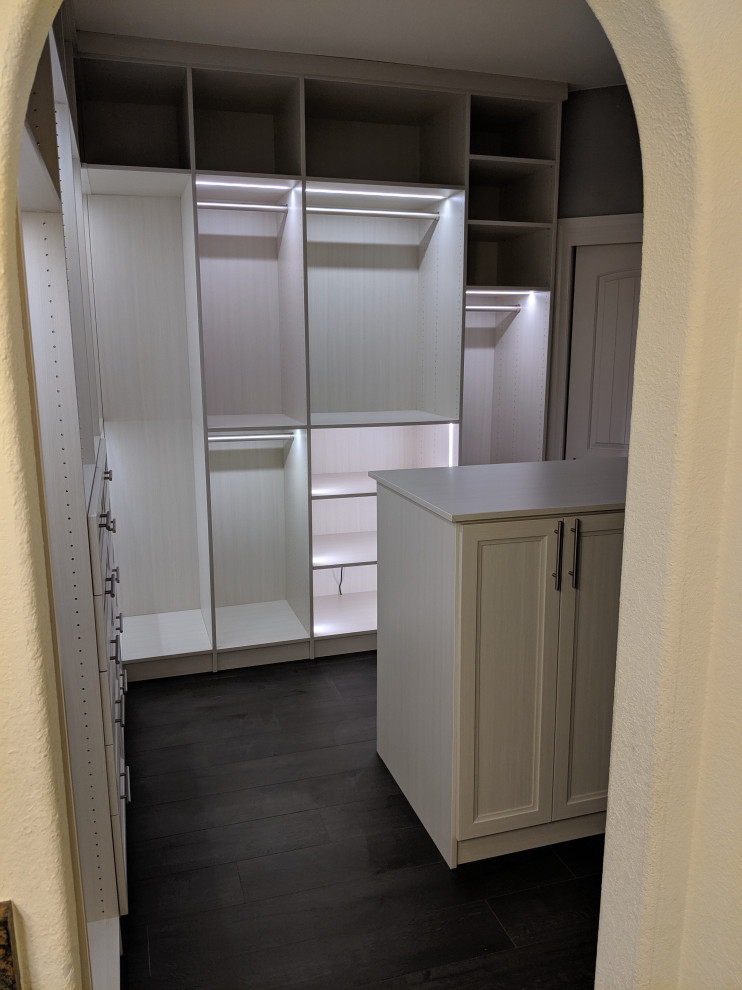 Mid-sized transitional women's dressing room with glass-front cabinets, light wood cabinets, laminate floors and grey floor.